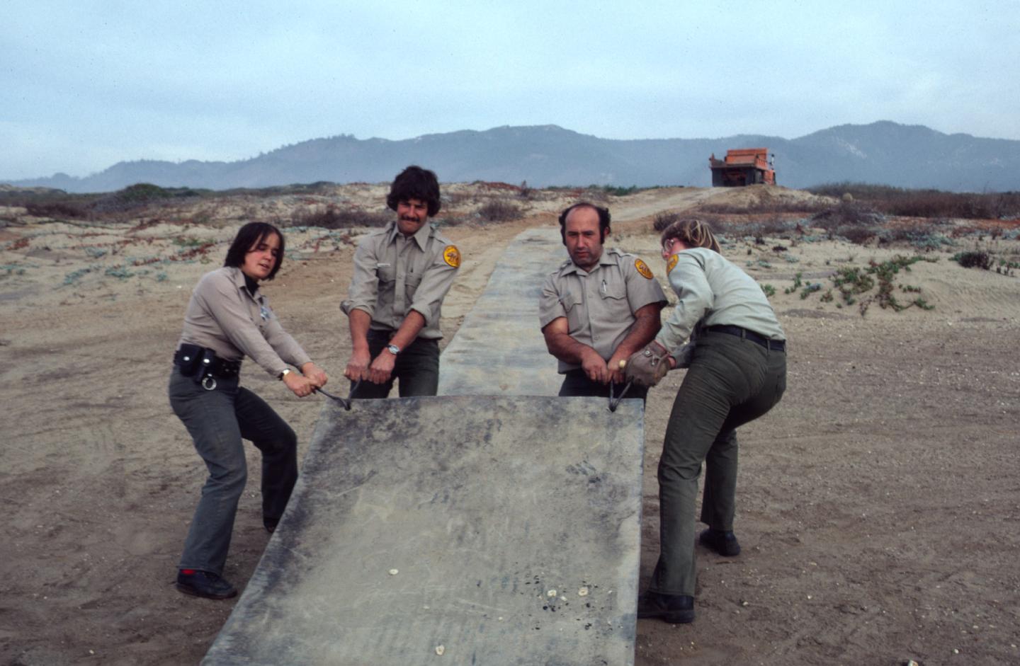 Nov 1980, Installing conveyor belt material for trail. Nina Gordon on far left with Chuck Edgemon, Dave Augustine and an unidentified parks staff.
